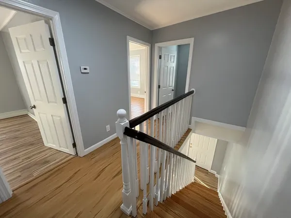 a view of staircase with wooden floor and white walls