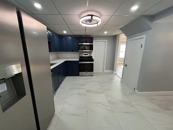 a large kitchen with stainless steel appliances granite countertop a refrigerator a sink a stove and a refrigerator