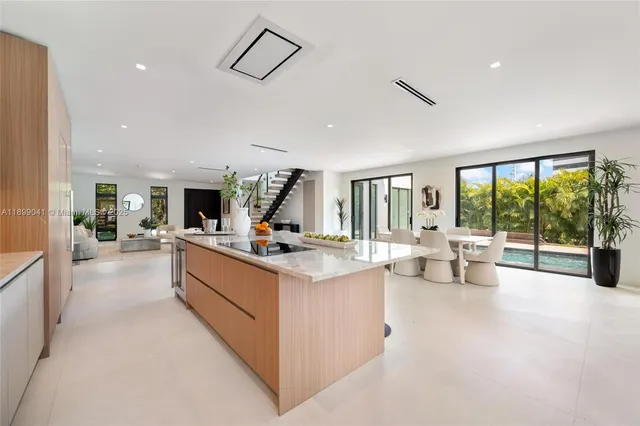 a large white kitchen with a large window and sitting area