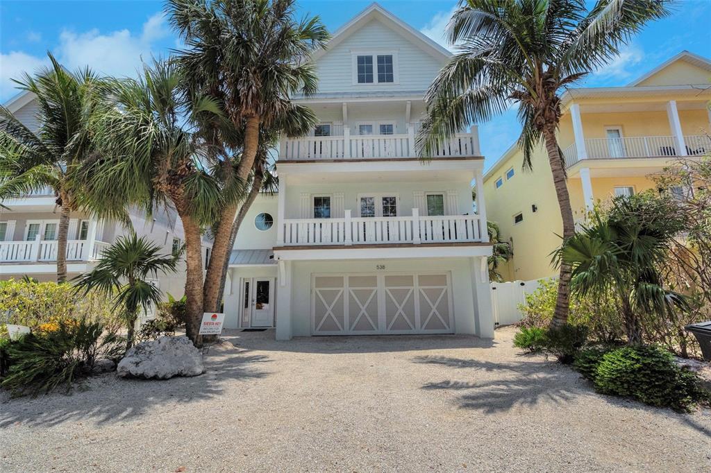 a front view of a house with a yard and palm trees