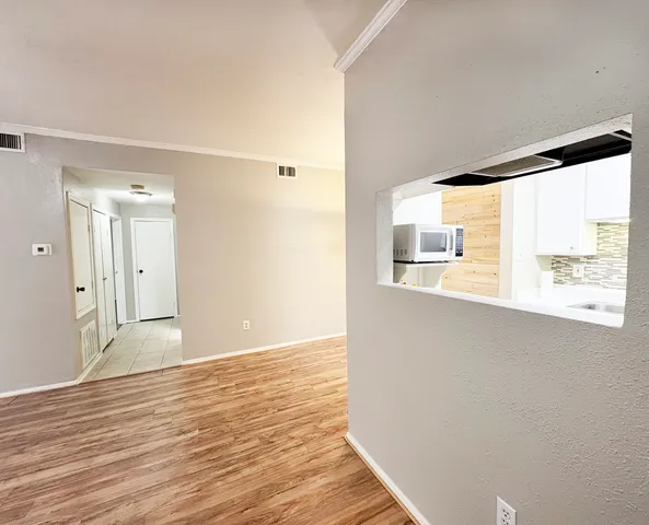 a view of an empty room with wooden floor and a window