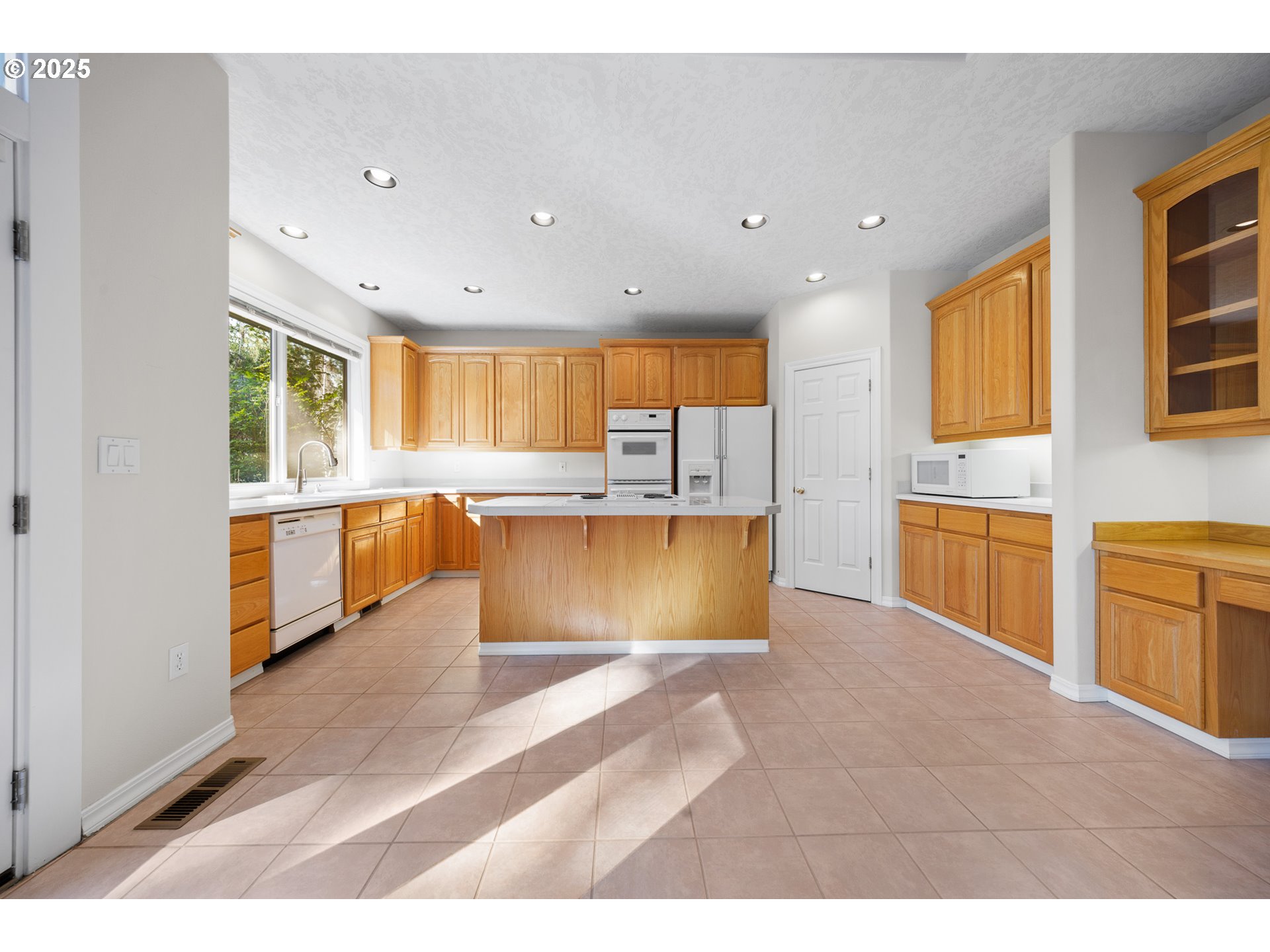 60799 Currant Way Bend, OR 97702 - Photo 8 of 28 a large kitchen with cabinets a sink a window and stainless steel appliances