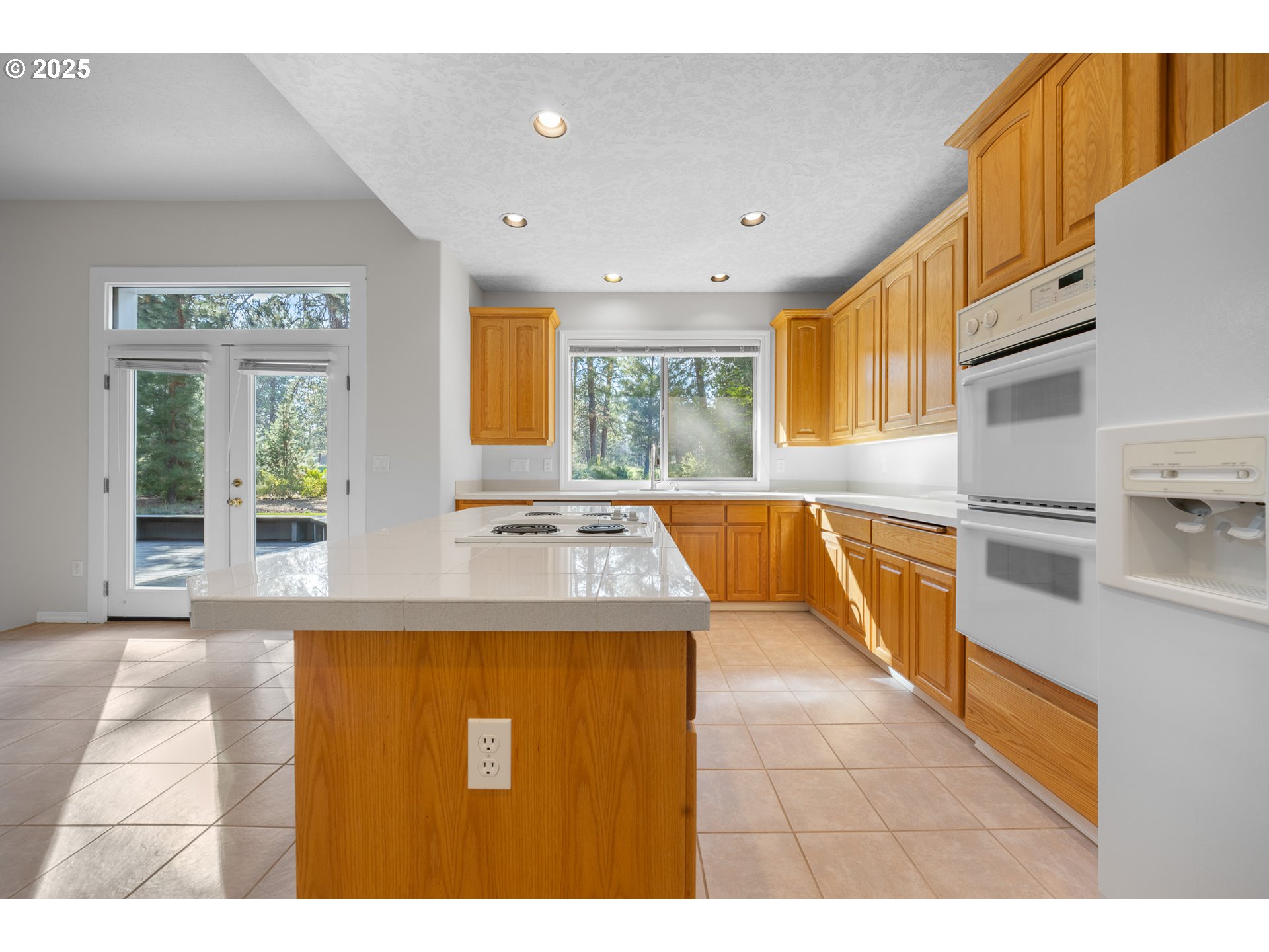60799 Currant Way Bend, OR 97702 - Photo 9 of 28 a kitchen with kitchen island a stove a sink a refrigerator and a counter top space