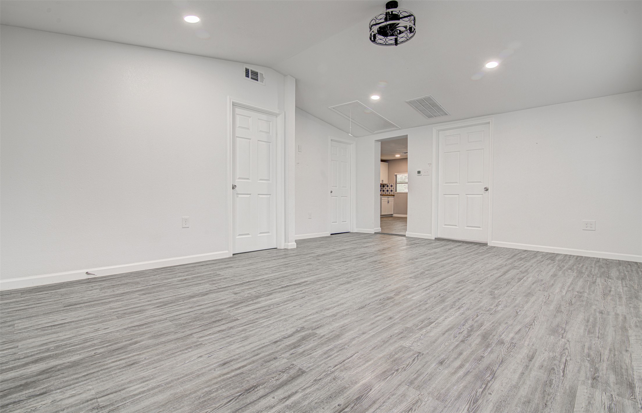 1807 San Jose Street Georgetown, TX 78626 - Photo 11 of 21 A spacious, airy room with elegant light gray wood-look flooring and multiple pristine white doors.