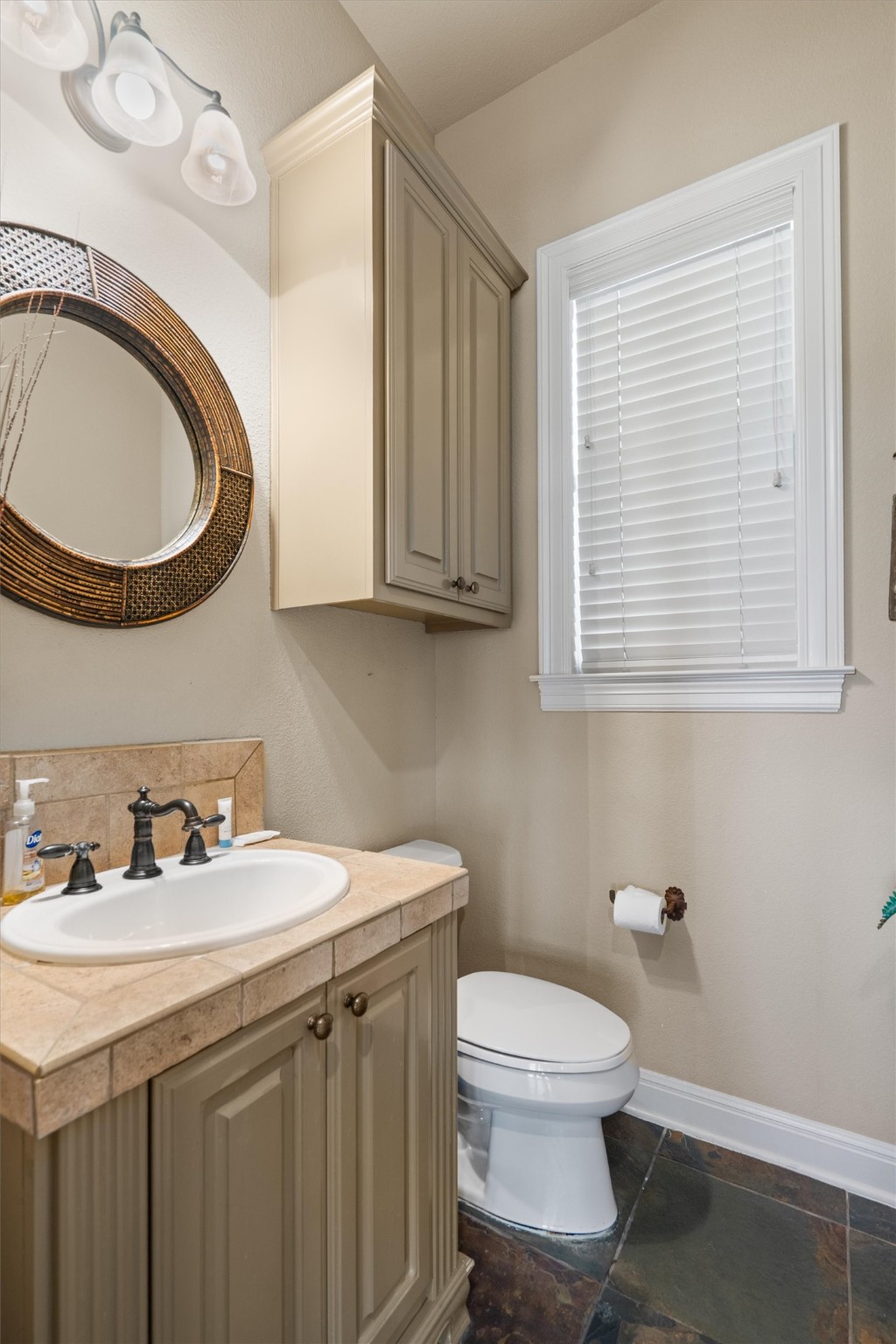 1017 Coventry Road Spicewood, TX 78669 - Photo 18 of 43 a bathroom with a toilet a sink a mirror and a window
