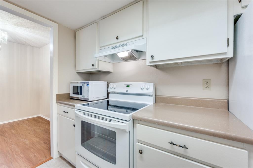 12830 Midway Road, Unit 1120 Dallas, TX 75244 - Photo 6 of 14 a kitchen with white cabinets and white appliances