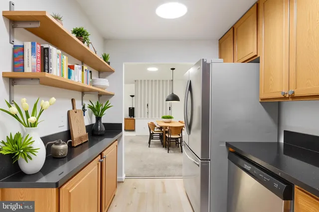 a kitchen with stainless steel appliances kitchen island granite countertop a table chairs in it and wooden floors