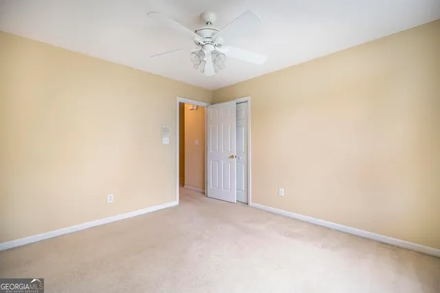 an empty room with a chandelier fan and windows