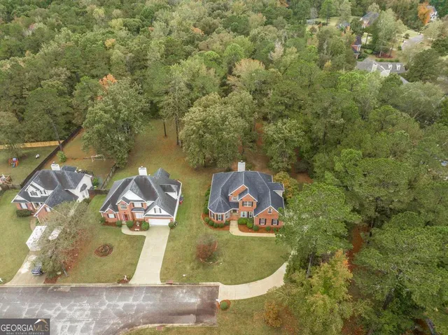 an aerial view of residential houses with outdoor space and trees