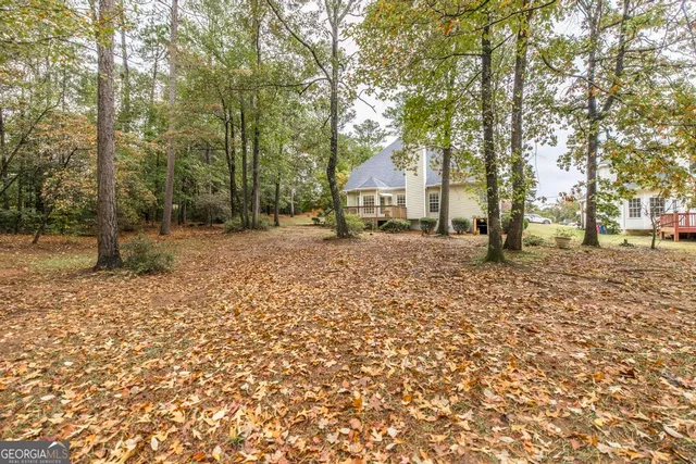 a backyard of a house with large trees and covered with wooden fence