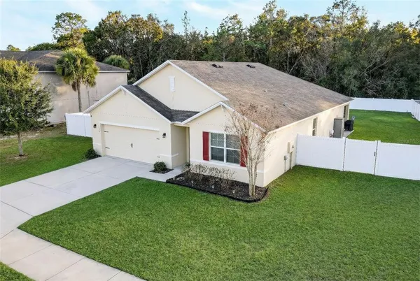 a aerial view of a white house sitting in big yard with large trees
