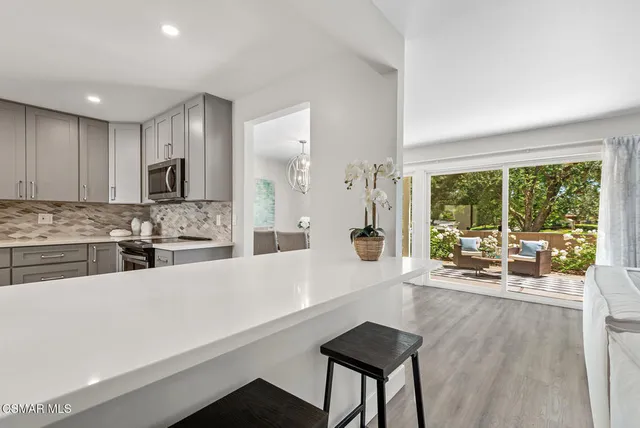 a large white kitchen with a large window and stainless steel appliances