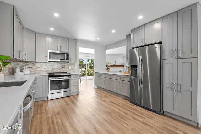 a kitchen with a refrigerator a stove top oven and wooden floor