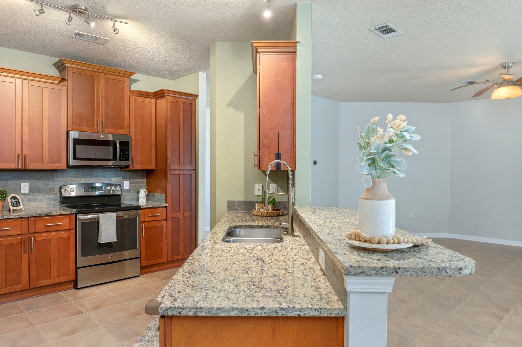 5280 Moore Loop Crestview, FL 32536 - Photo 16 of 54 a kitchen with stainless steel appliances granite countertop a stove refrigerator and microwave