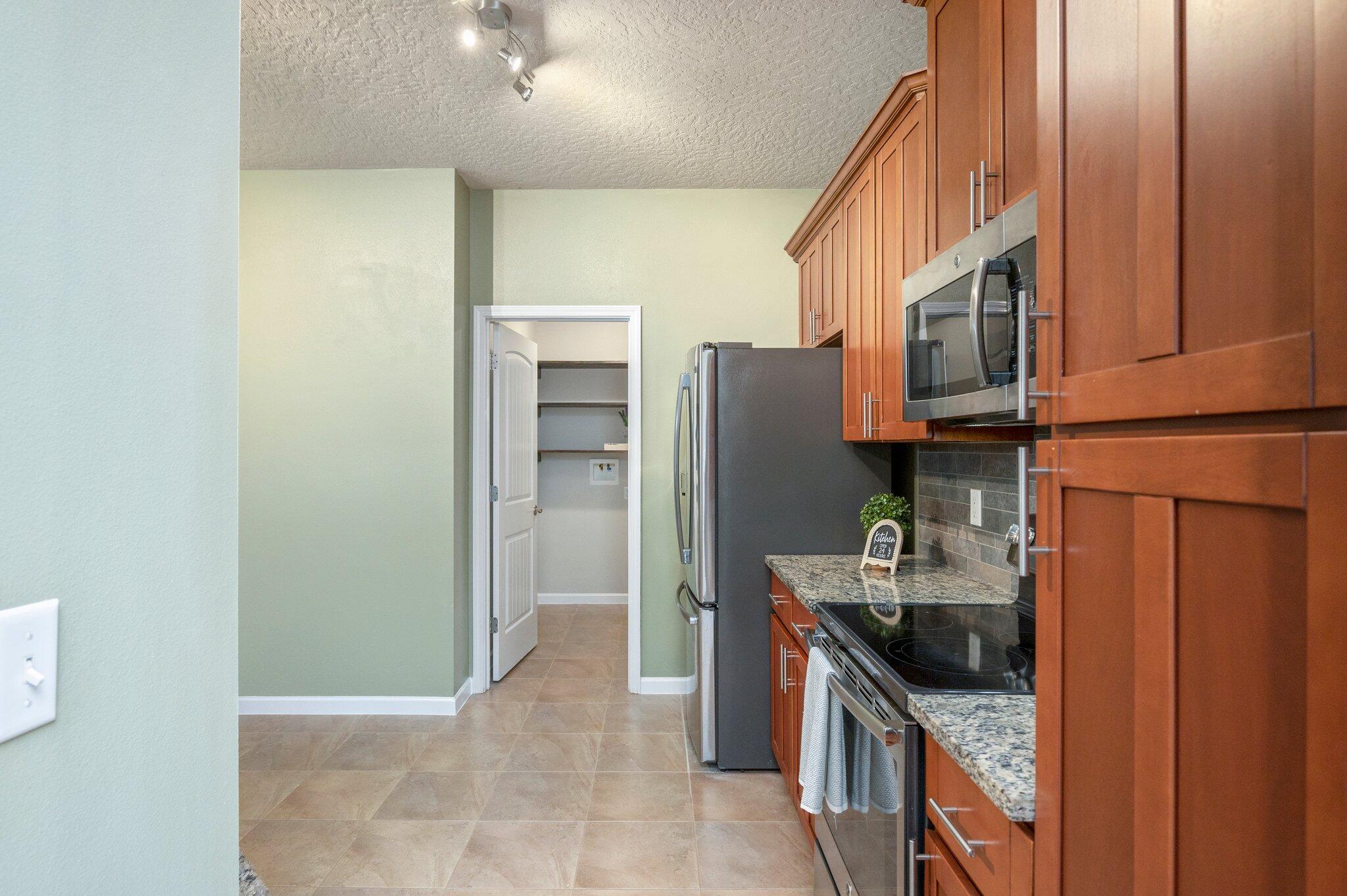 5280 Moore Loop Crestview, FL 32536 - Photo 19 of 54 a kitchen with stainless steel appliances granite countertop a refrigerator a stove and a sink with wooden cabinets