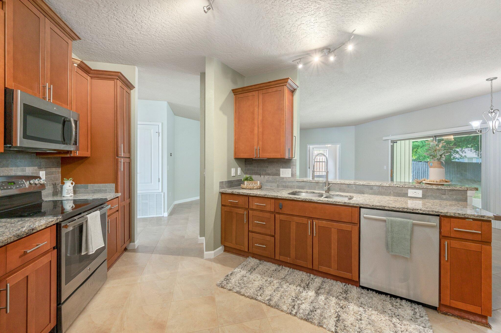 5280 Moore Loop Crestview, FL 32536 - Photo 20 of 54 a large kitchen with granite countertop a sink and dishwasher a stove top oven with wooden floor