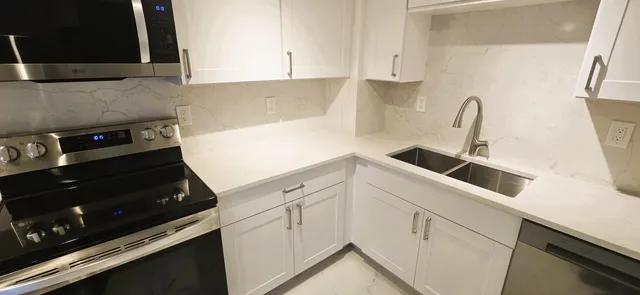a kitchen with granite countertop white cabinets and black appliances