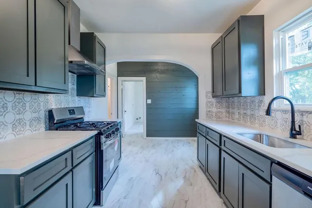 a kitchen with stainless steel appliances a sink stove and cabinets