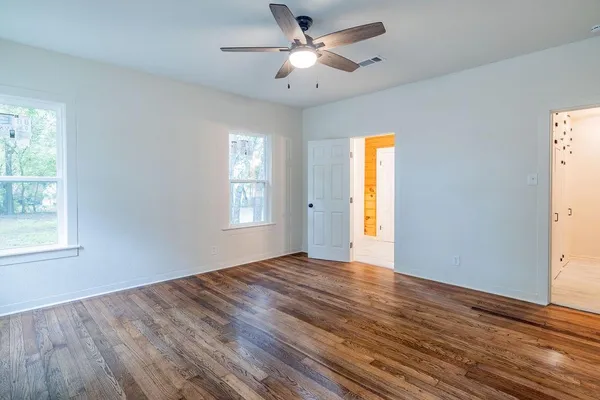 a view of empty room with wooden floor and fan