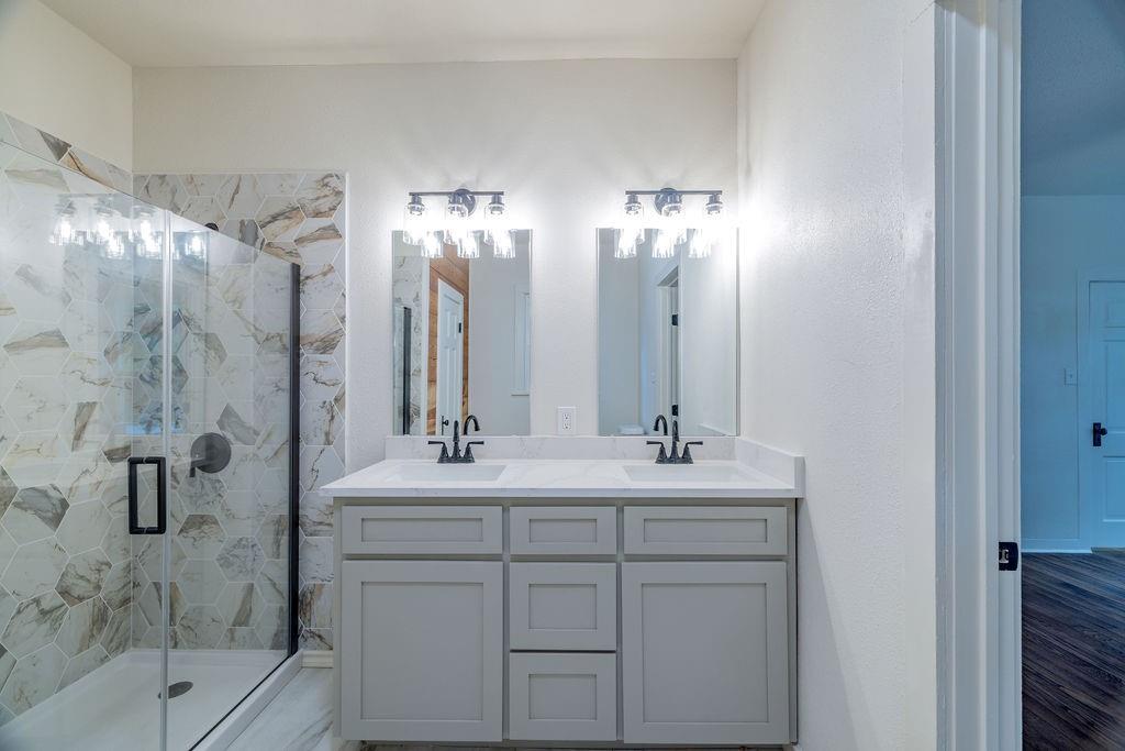 711 Fannin Street Nocona, TX 76255 - Photo 20 of 35 a bathroom with a double vanity sink mirror and shower