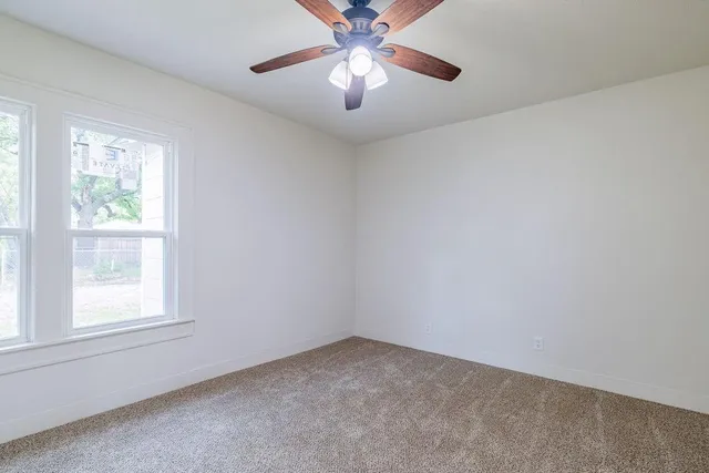 an empty room with a window and a fan