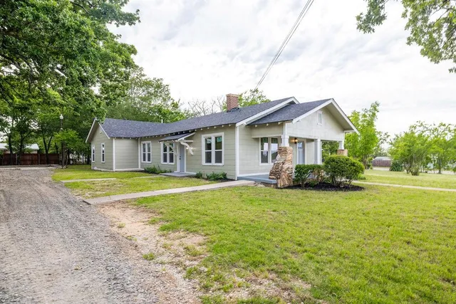 a view of a house with a big yard and large trees