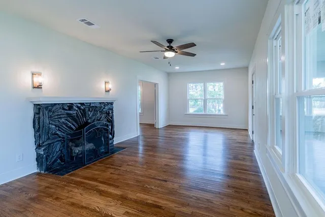 a big room with wooden floor a ceiling fan and windows