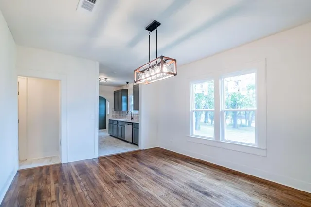 a view of empty room with wooden floor and windows