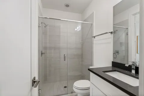 a bathroom with a granite countertop shower a toilet and a sink