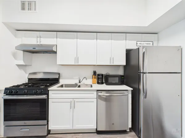 a kitchen with stainless steel appliances white cabinets and a refrigerator