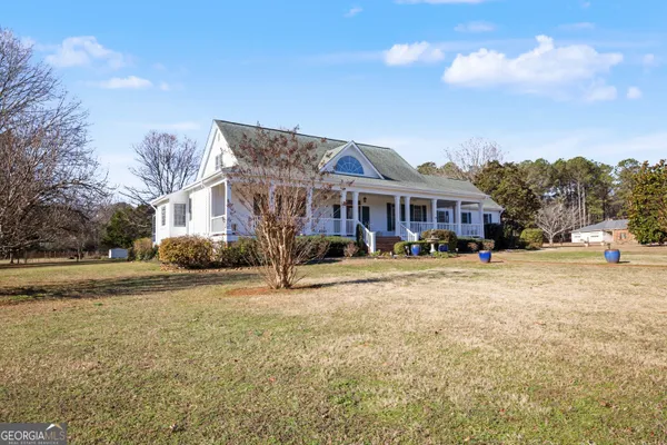 a view of a white house with a yard in front of it