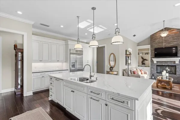 a kitchen with stainless steel appliances granite countertop a refrigerator a stove a sink a dining table and chairs with wooden floor