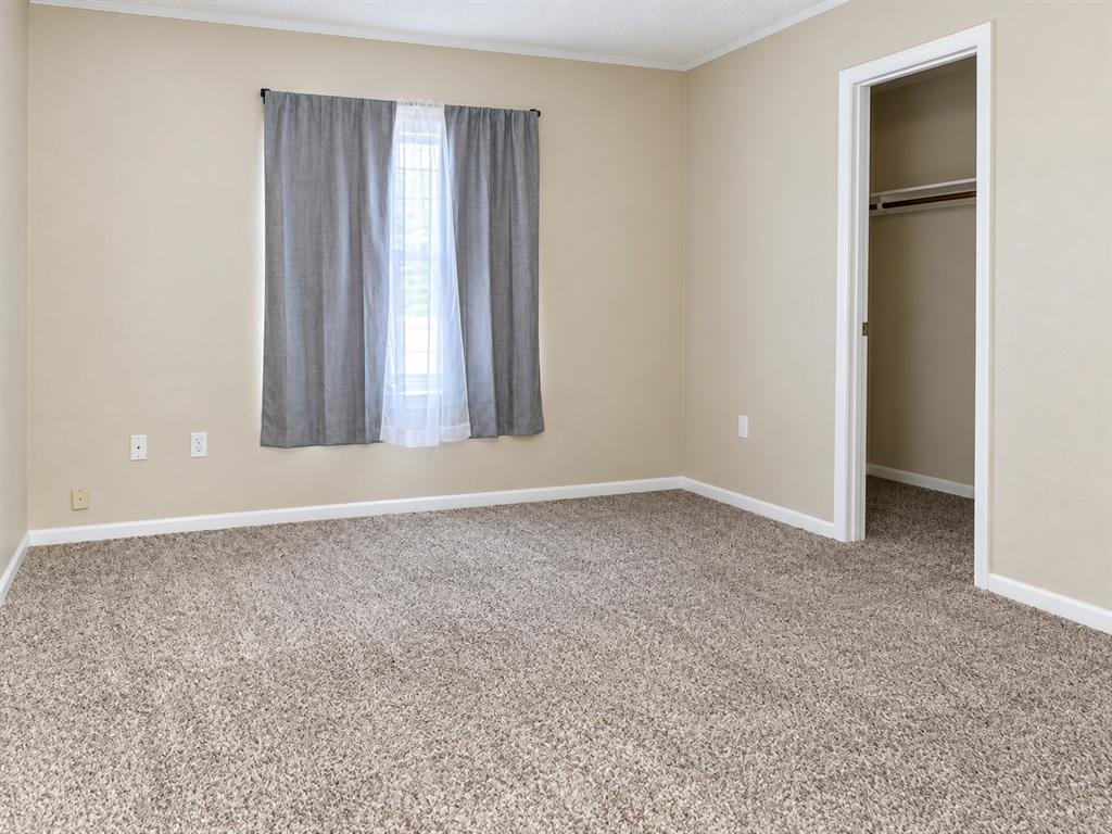 301 South Coppell Road, Unit 51 Coppell, TX 75019 - Photo 14 of 20 Carpeted room featuring a window with white trim, tan wall paint, and a built-in closet with a hanging rod