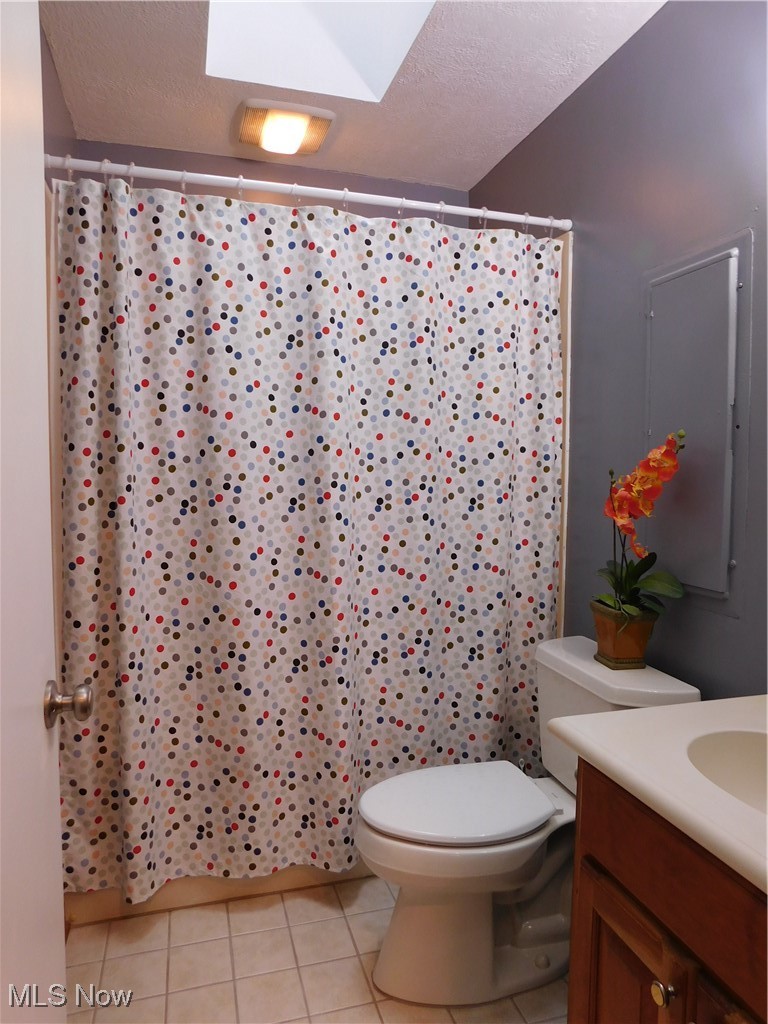 987 Hampton Ridge Drive Akron, OH 44313 - Photo 28 of 49 Full bathroom featuring light tile patterned flooring, a textured ceiling, a shower with shower curtain, vanity, and a skylight
