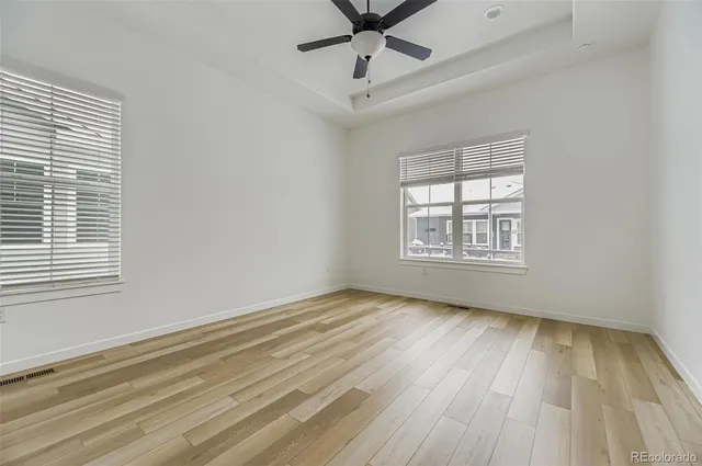 a view of empty room with wooden floor and ceiling fan