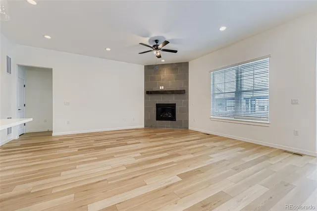 an empty room with chandelier fan and wooden floor