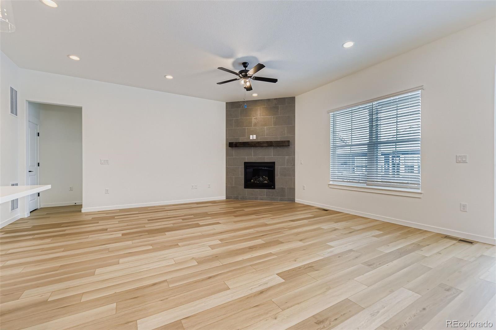 8905 South Riviera Way Aurora, CO 80016 - Photo 4 of 27 an empty room with chandelier fan and wooden floor