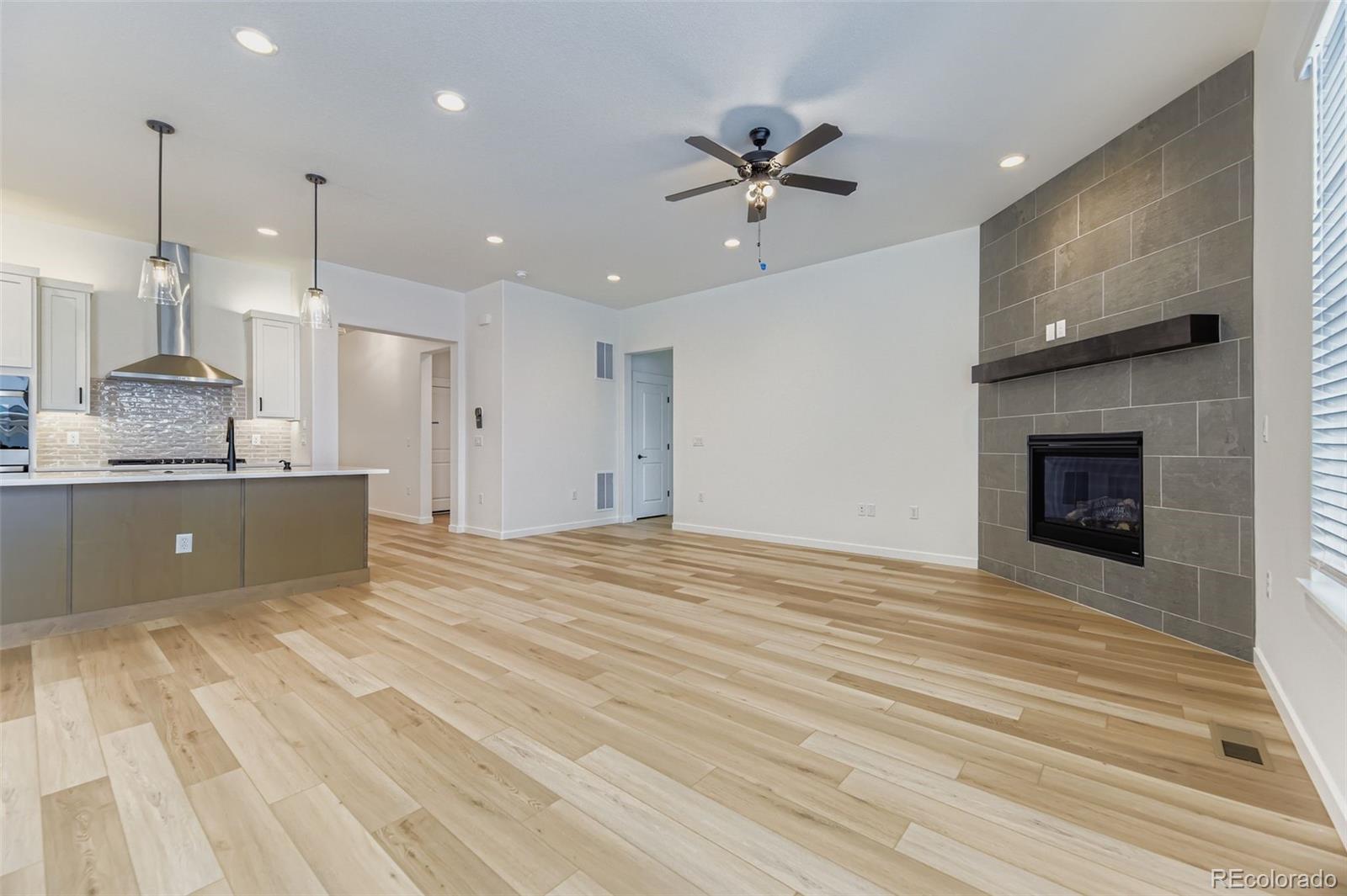 8905 South Riviera Way Aurora, CO 80016 - Photo 6 of 27 a view of an empty room and kitchen with fireplace ceiling fan
