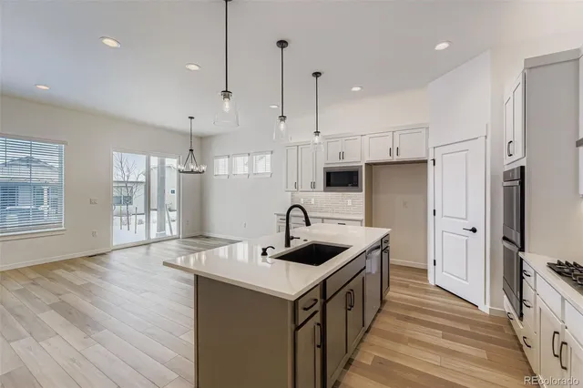 a kitchen with stainless steel appliances a stove a sink dishwasher a refrigerator white cabinets and wooden floor