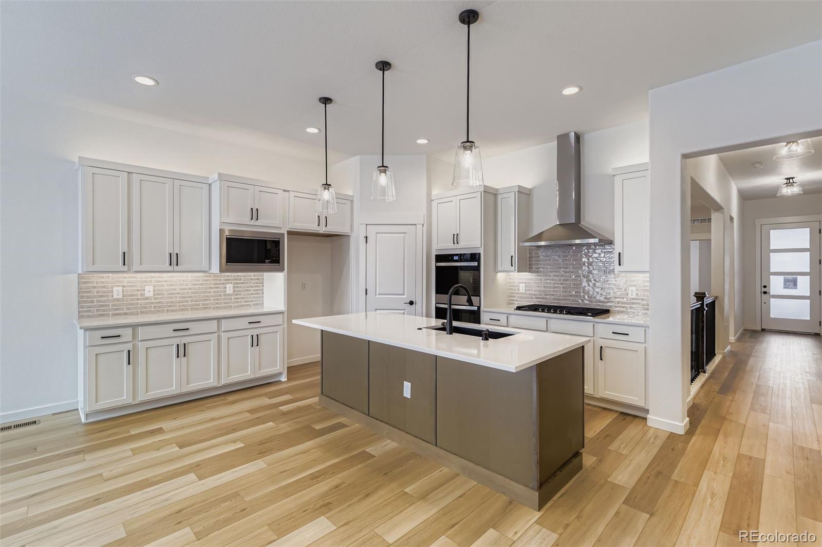 8905 South Riviera Way Aurora, CO 80016 - Photo 9 of 27 a kitchen with stainless steel appliances a stove a sink dishwasher a refrigerator white cabinets and wooden floor
