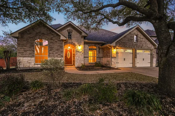 a view of a house with a small yard and large tree
