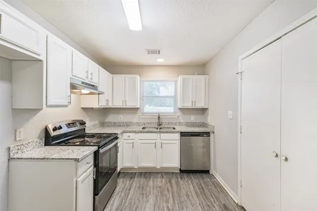 a kitchen with stainless steel appliances a sink stove and cabinets