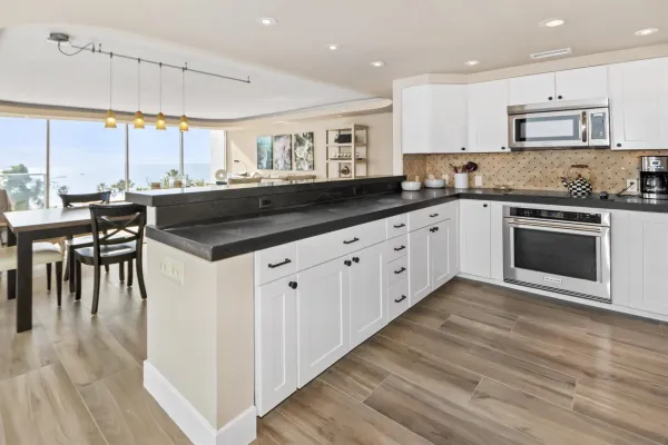 a kitchen with granite countertop a stove a sink and white cabinets with wooden floor