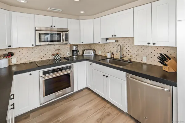 a kitchen with granite countertop white cabinets and stainless steel appliances