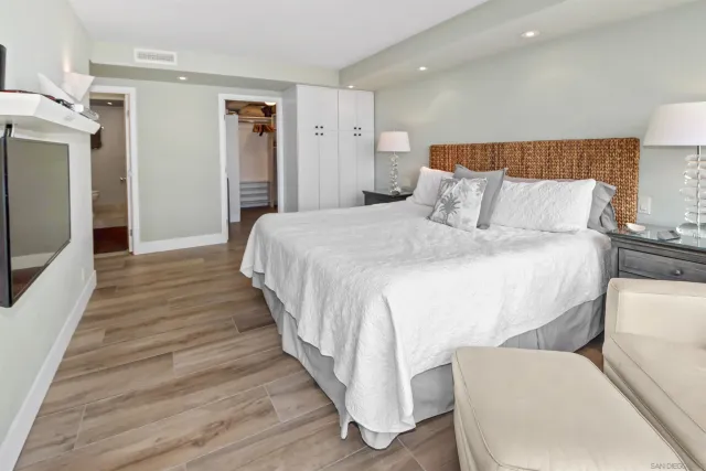 a spacious bedroom with a bed and a flat screen tv