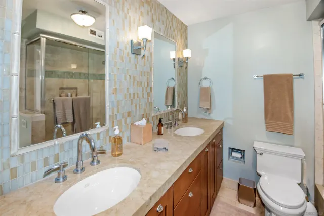 a bathroom with a double vanity sink toilet and mirror