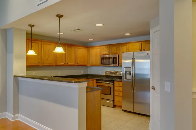 a kitchen with stainless steel appliances granite countertop a sink a stove and a refrigerator