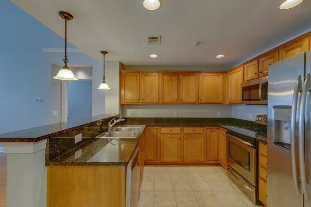 a kitchen with stainless steel appliances granite countertop a sink a stove and a refrigerator