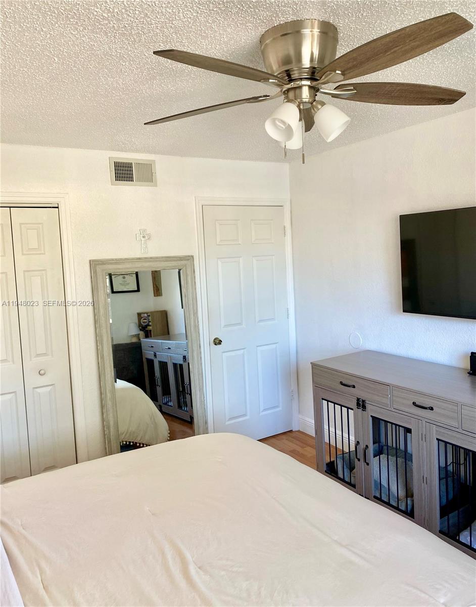 15680 Southwest 106th Lane, Unit 804 Miami, FL 33196 - Photo 24 of 32 a bedroom with a bed and a flat tv screen on dresser