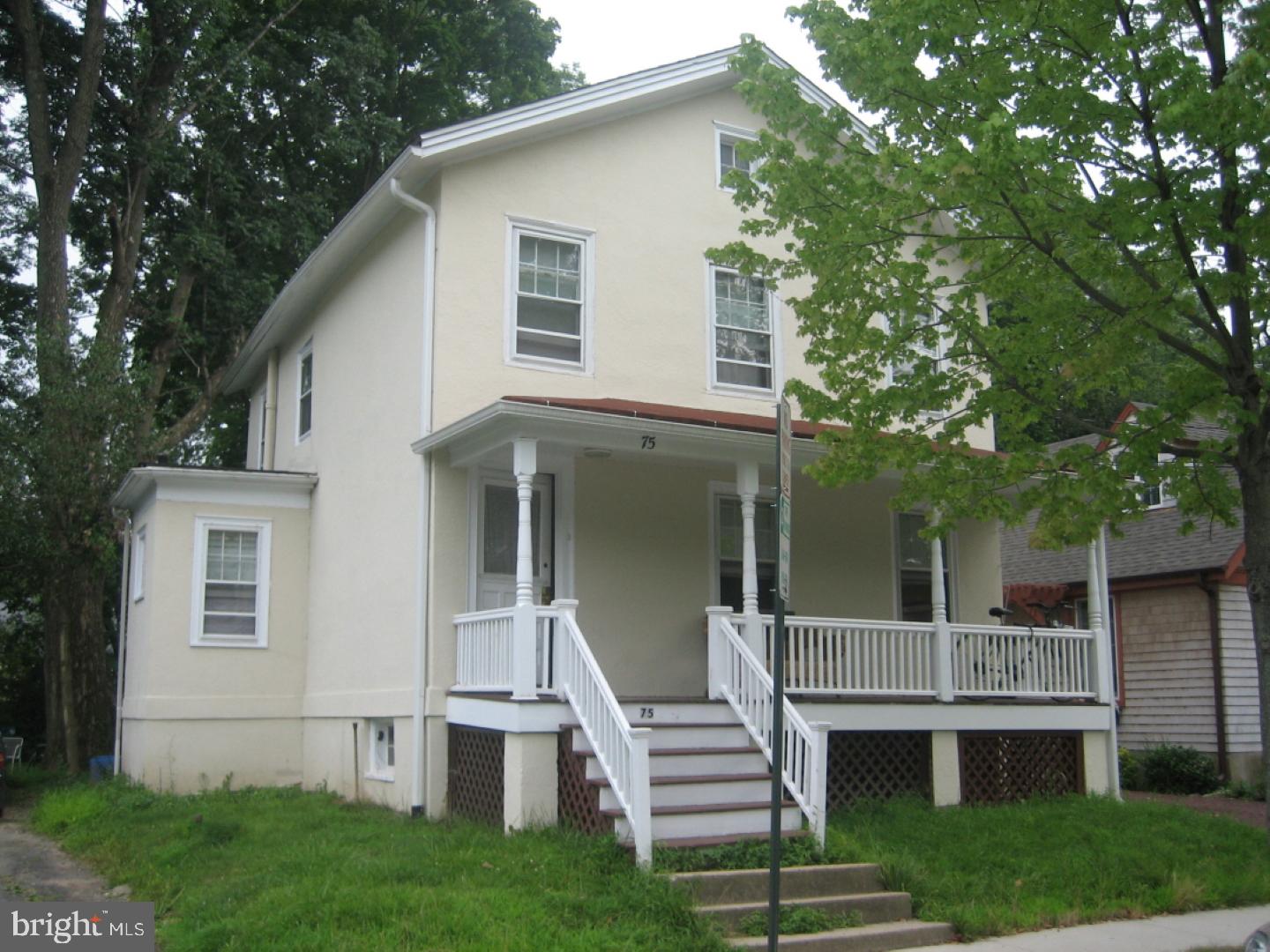 a view of a white house with a large window and wooden fence